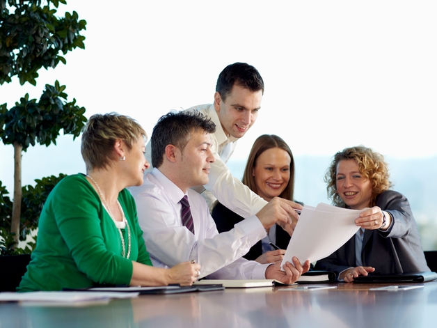 Gruppe af medarbejdere diskuterer ved et stort konferencebord.