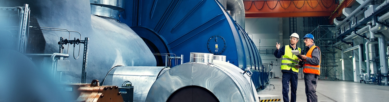 Nærbillede af en tekniker foran en turbine på et kraftværk