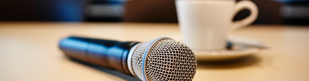 Pressekonferencestemning: mikrofon og kaffekop på et bord.