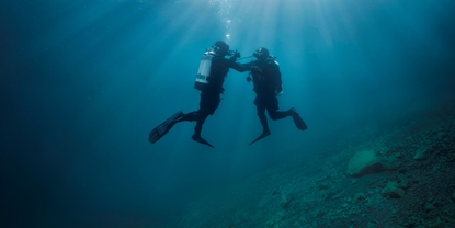 Undervandsscene: En dykker hjælper en anden dykker, som har problemer med luftforsyningen.