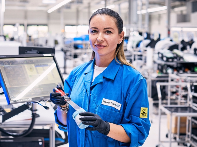 Produktionsarbejder står ved en samlestation.