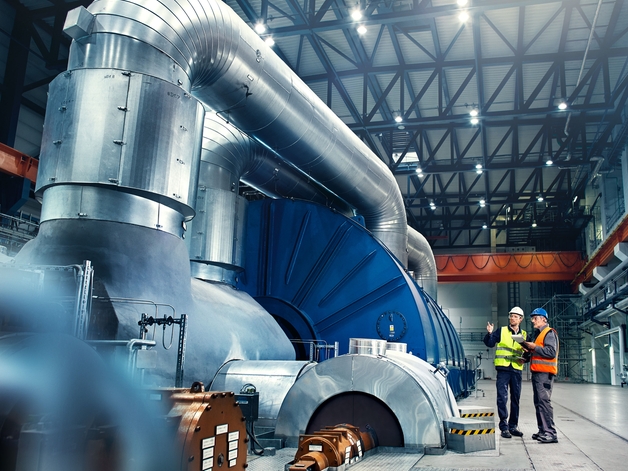 To teknikere i samtale ved siden af en energiproduktionsturbine.