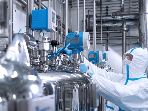Tekniker i en hygiejnedragt betjener et instrument i et life science-miljø.